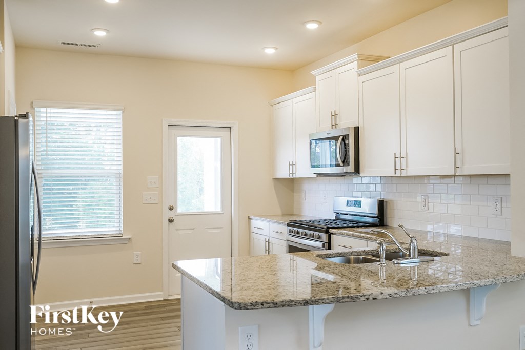 a kitchen with white cabinets and a granite counter top