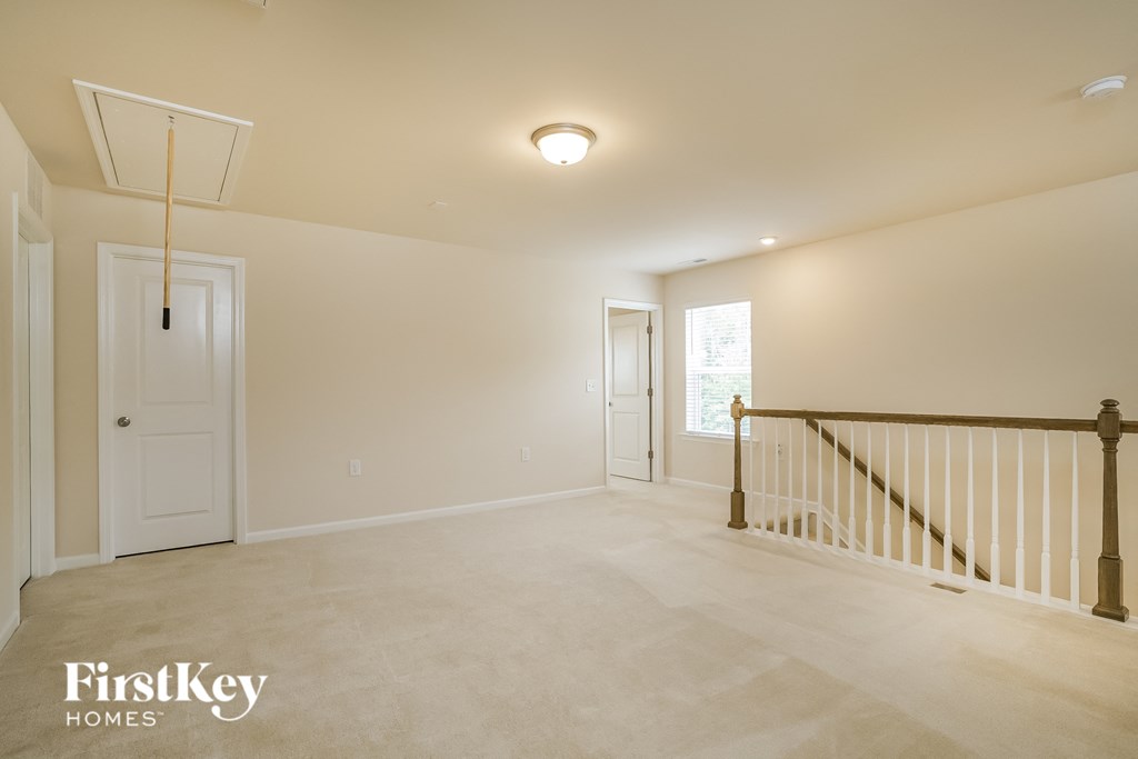 an empty living room with a staircase and a white door