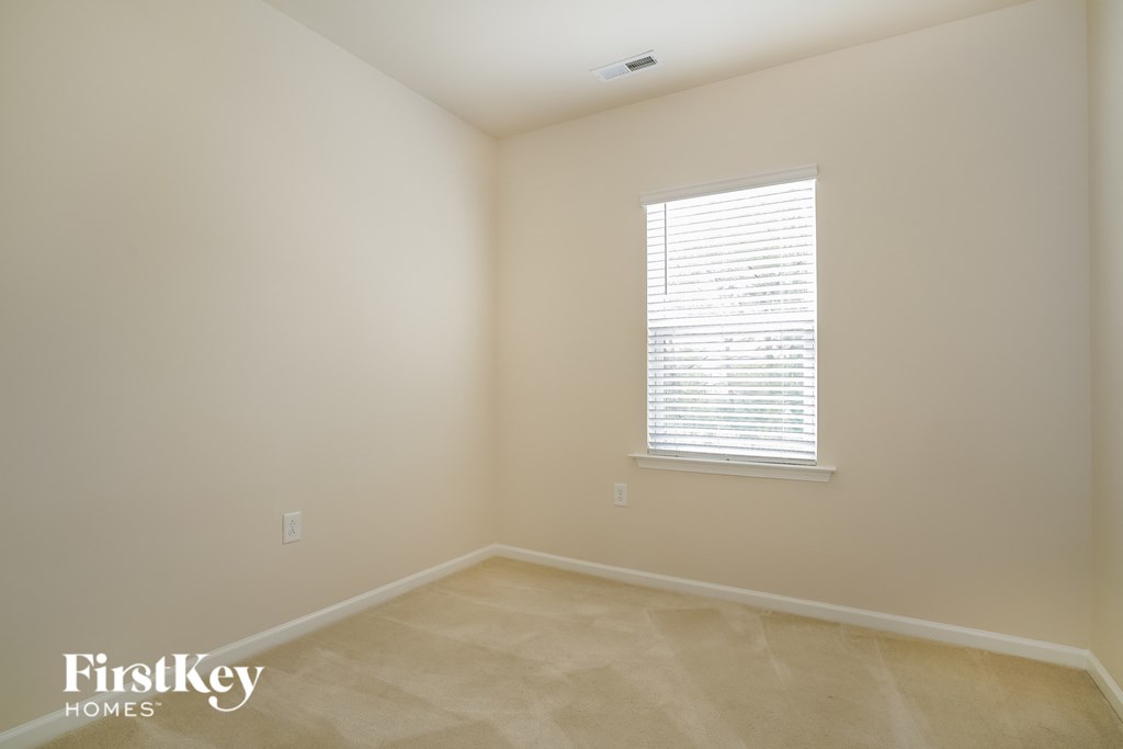 a room with beige walls and a window with a window blind