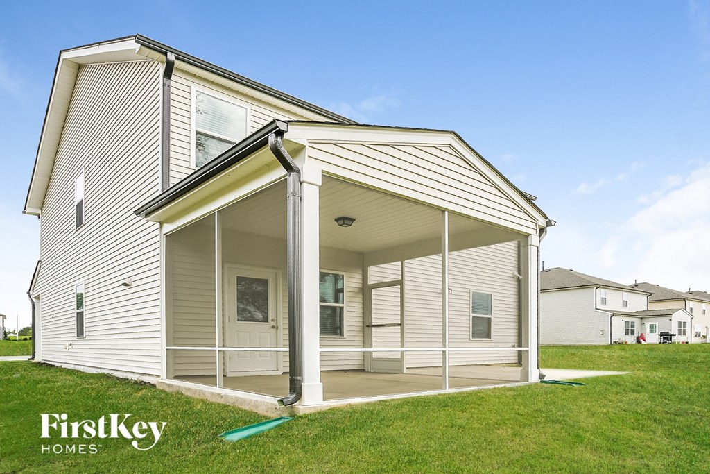 a small white house with a porch on a lawn