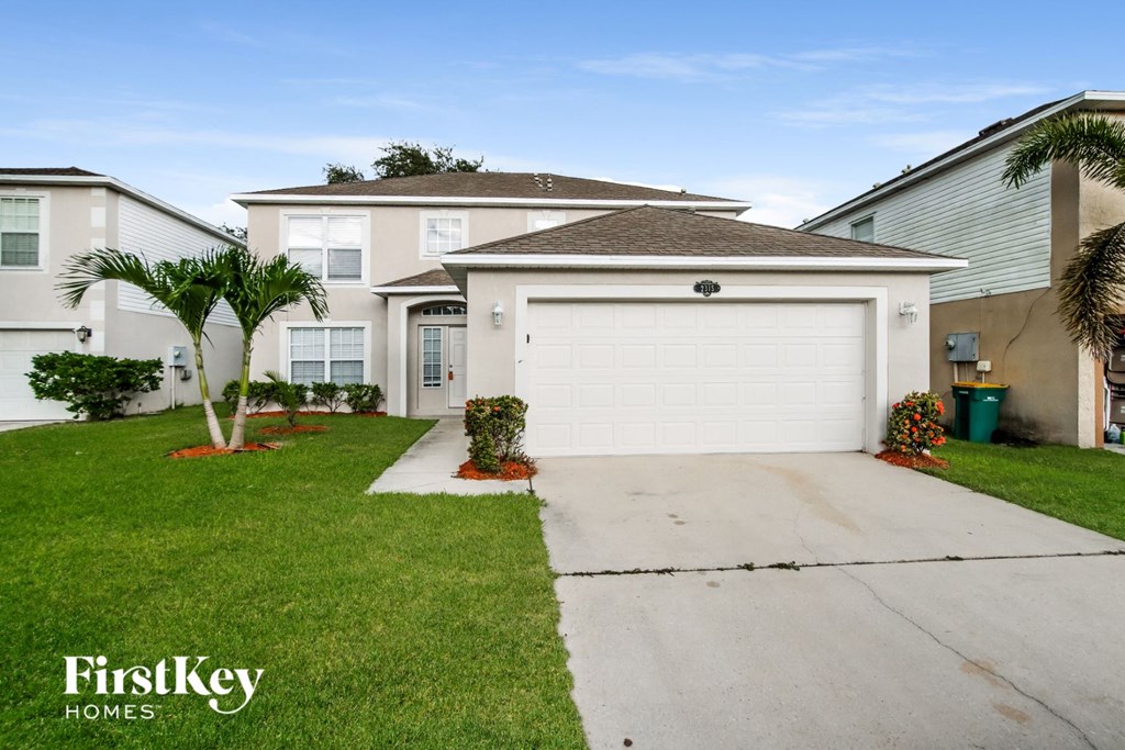 A house with a white garage door and a palm tree in front.