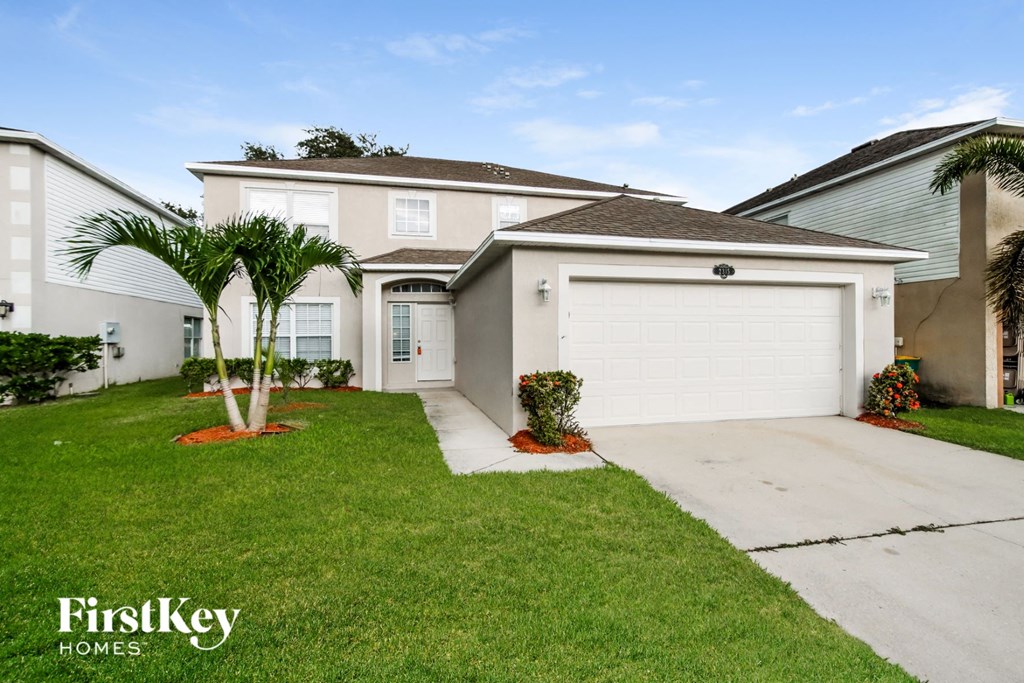 A house with a white garage door and a palm tree in front.