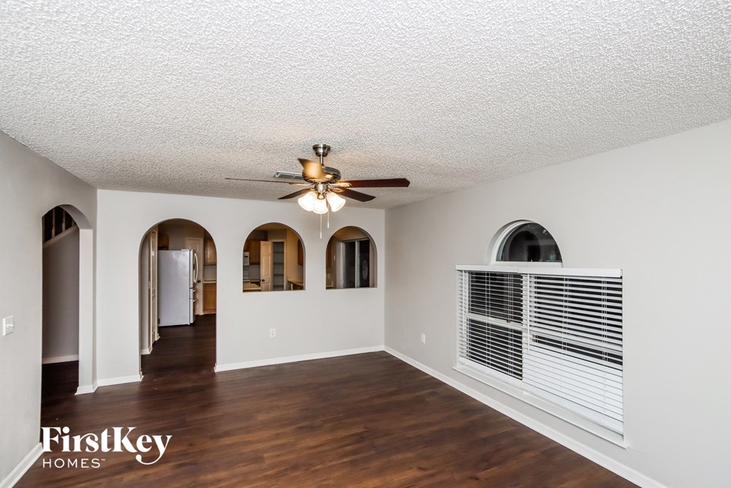 A spacious room with a ceiling fan and arched windows.