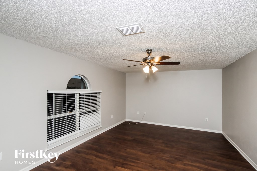 A room with a ceiling fan and a window with blinds.