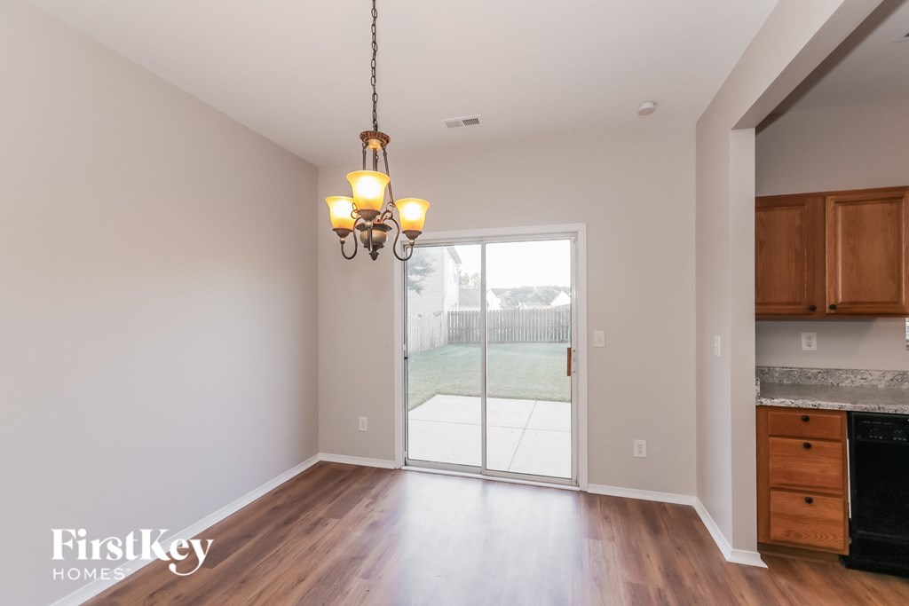 an empty living room with a door to the backyard and a chandelier
