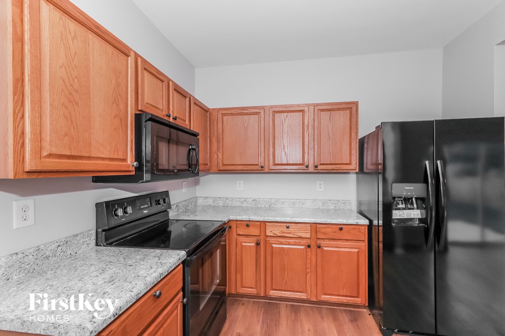 a kitchen with wood cabinets and black appliances and granite counter tops