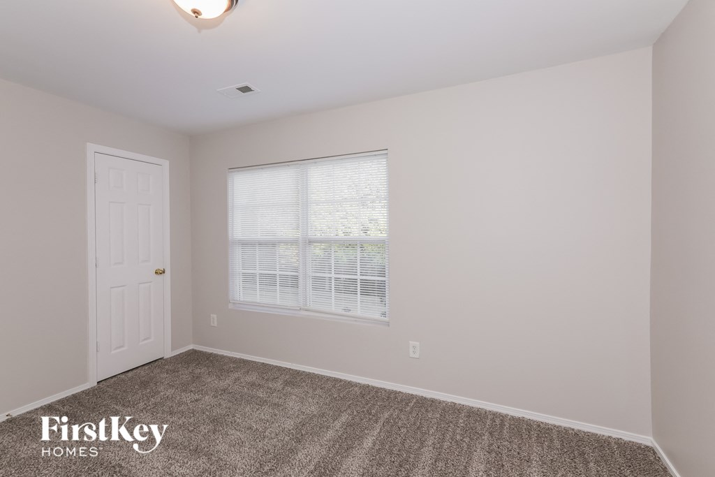 a bedroom with a door and a window and a carpeted floor