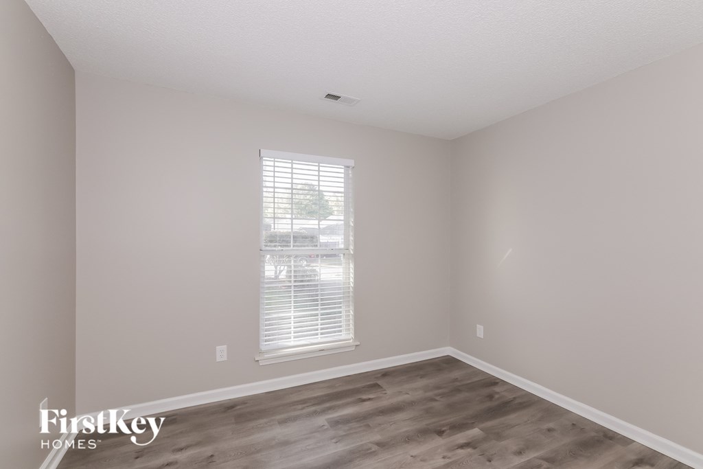 a bedroom with wood floors and white walls and a window