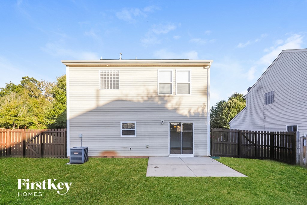 the back of a white house with a yard and a black fence