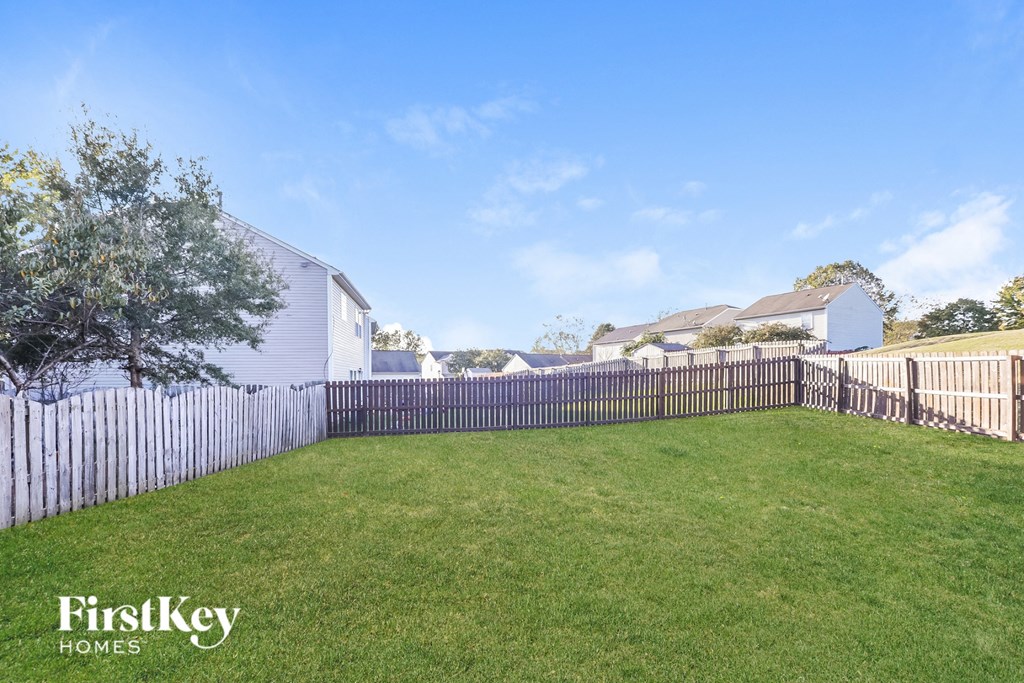 a backyard with a white fence and a green lawn