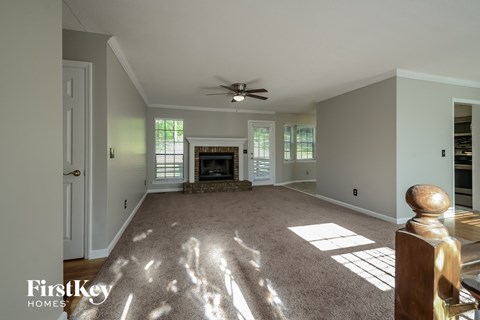 A spacious living room with a fireplace and a ceiling fan.