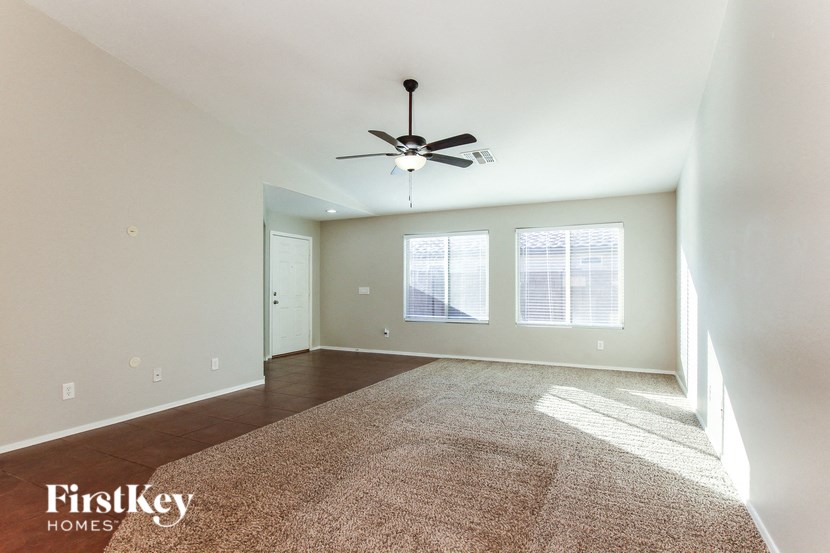 an empty living room with a ceiling fan