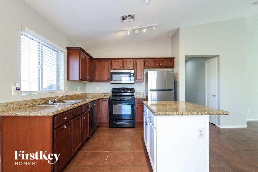 a kitchen with wooden cabinets and granite counter tops and a stove and refrigerator
