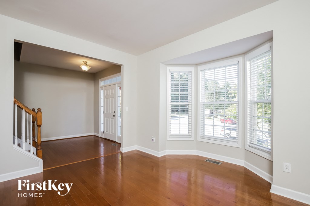 A room with wooden floors and a staircase leading to another room.