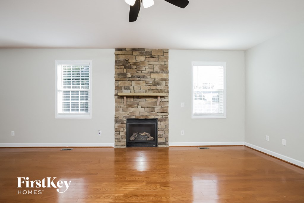 A room with a stone fireplace and wooden floors.