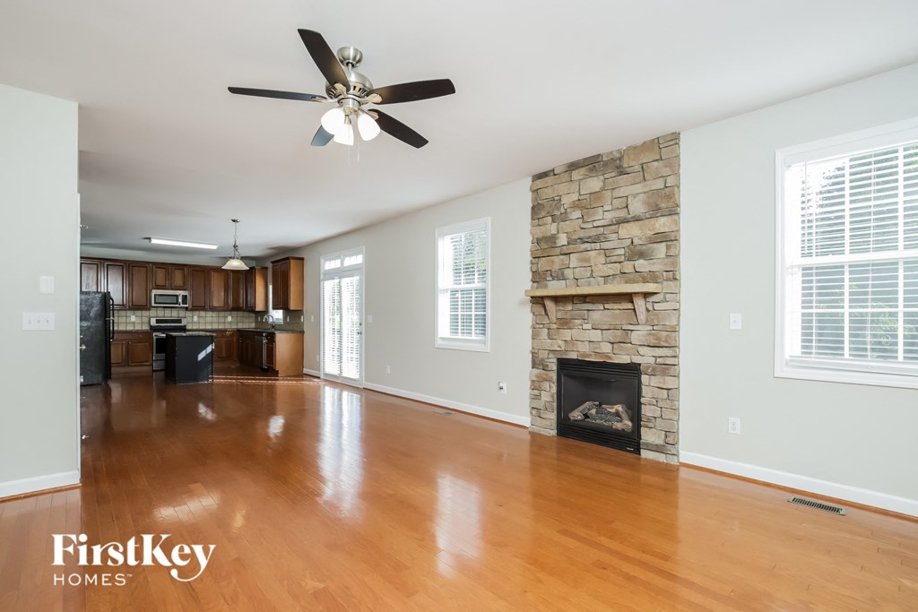 A spacious living room with a fireplace and a ceiling fan.