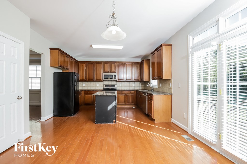 A kitchen with wooden cabinets and a black fridge.