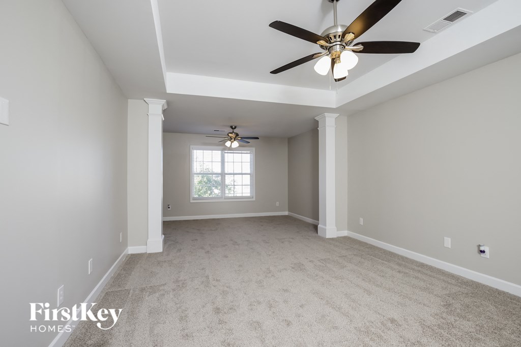 A spacious room with a ceiling fan and a window.