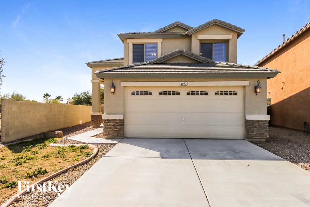 A modern house with a large driveway in front.