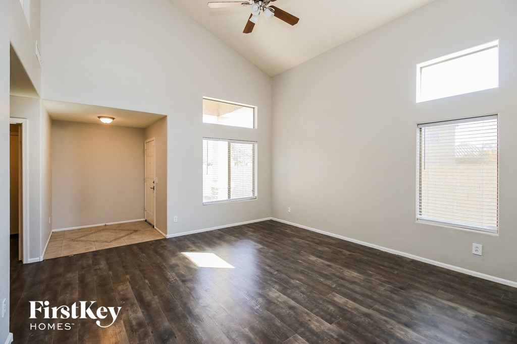 A spacious room with wooden flooring and a ceiling fan.