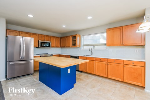 A kitchen with a blue island and wooden cabinets.