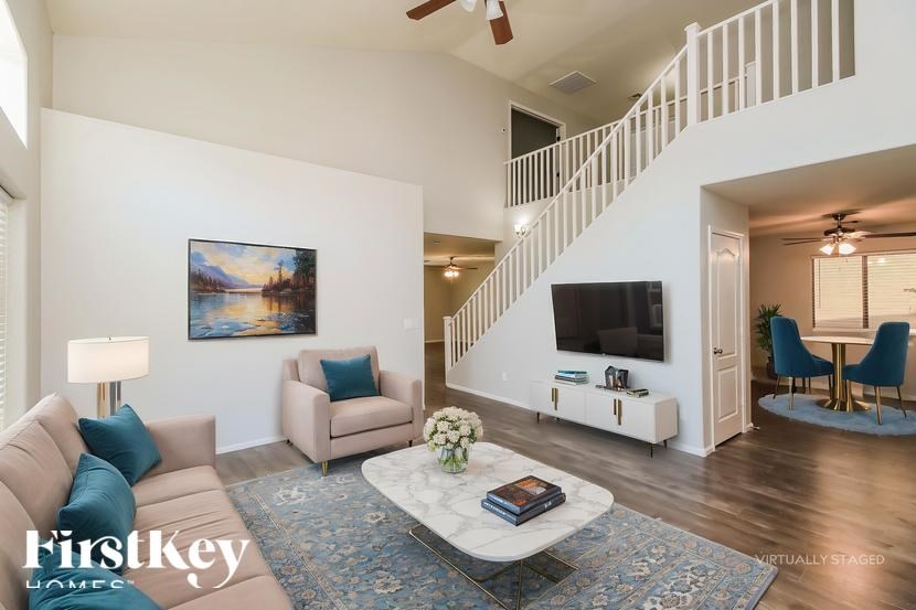 A living room with a staircase and a painting on the wall.