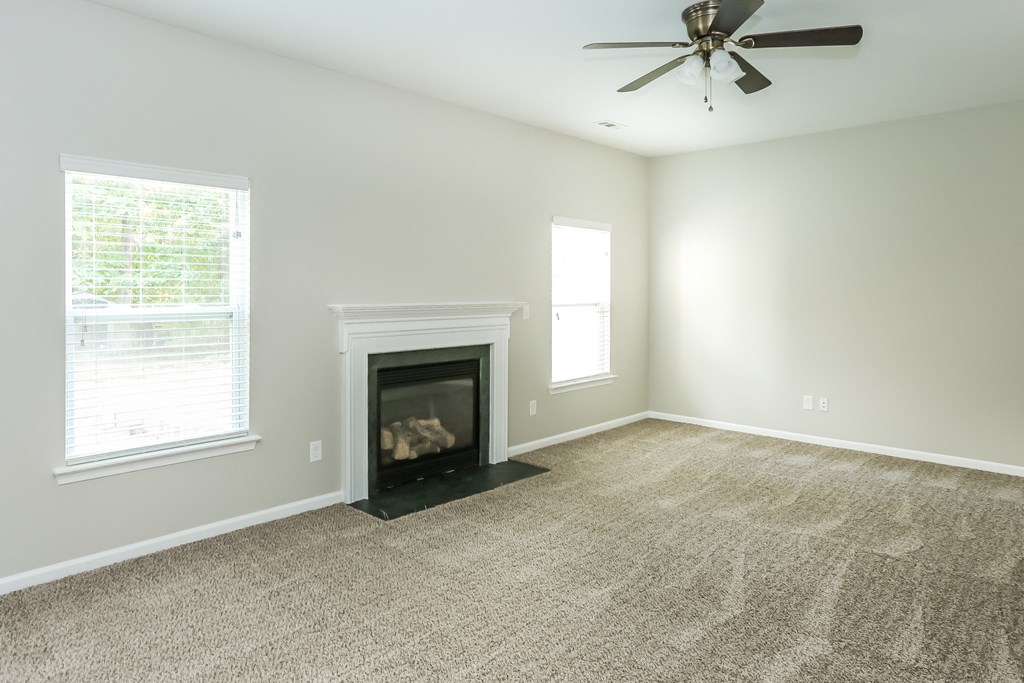 an empty living room with a fireplace and a ceiling fan