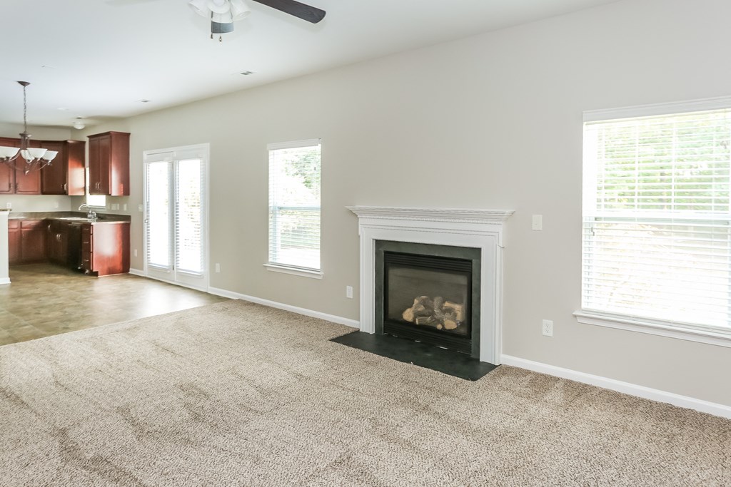 an empty living room with a fireplace and a kitchen