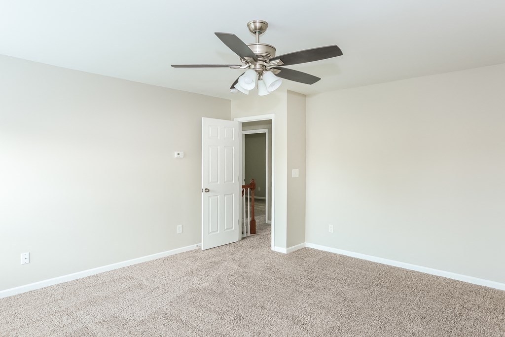 an empty living room with a ceiling fan