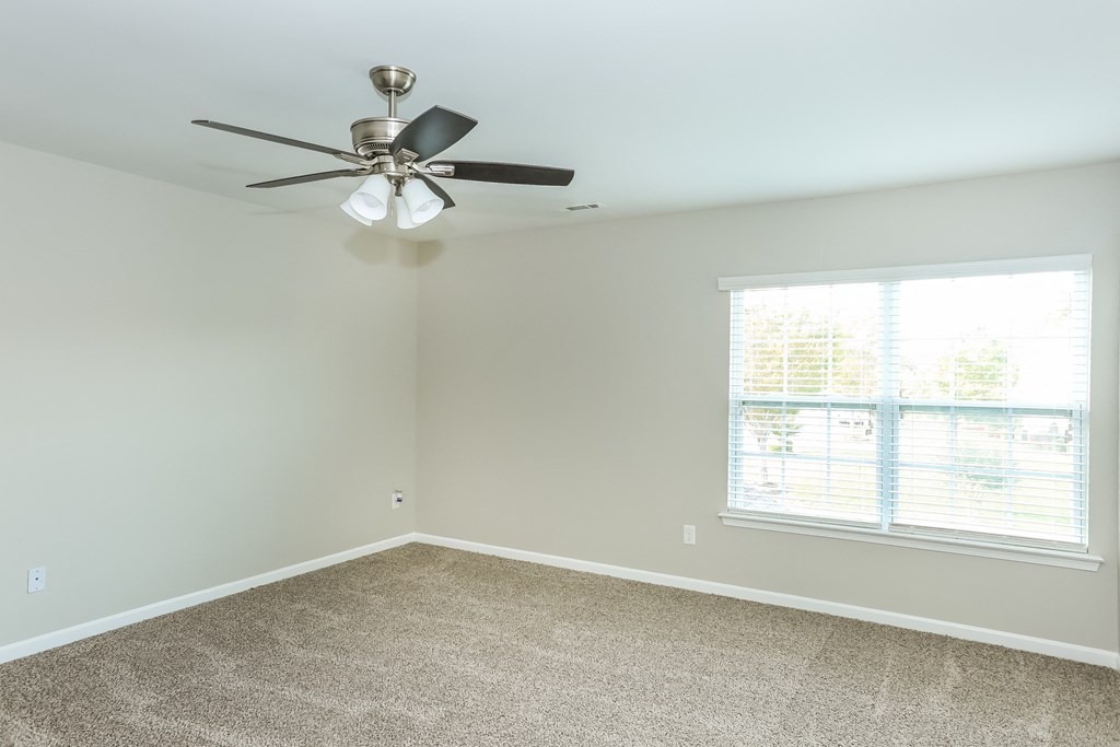 an empty room with a ceiling fan and a window