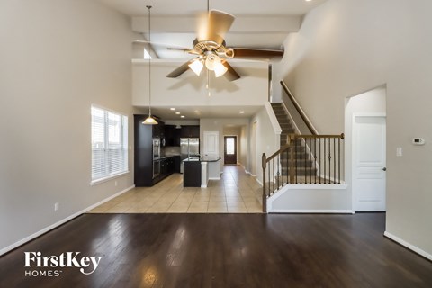 A spacious living room with a staircase and a ceiling fan.