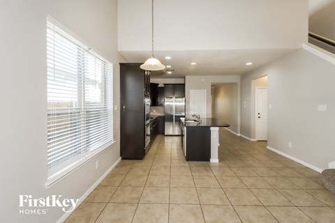 A spacious kitchen with a black refrigerator and white cabinets.