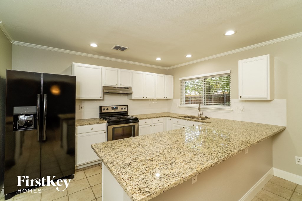 A kitchen with granite countertops and white cabinets.