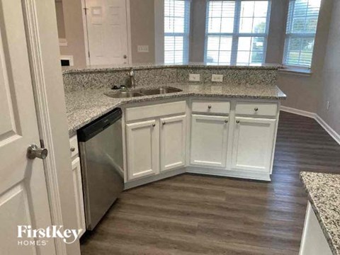 A kitchen with white cabinets and a granite countertop.