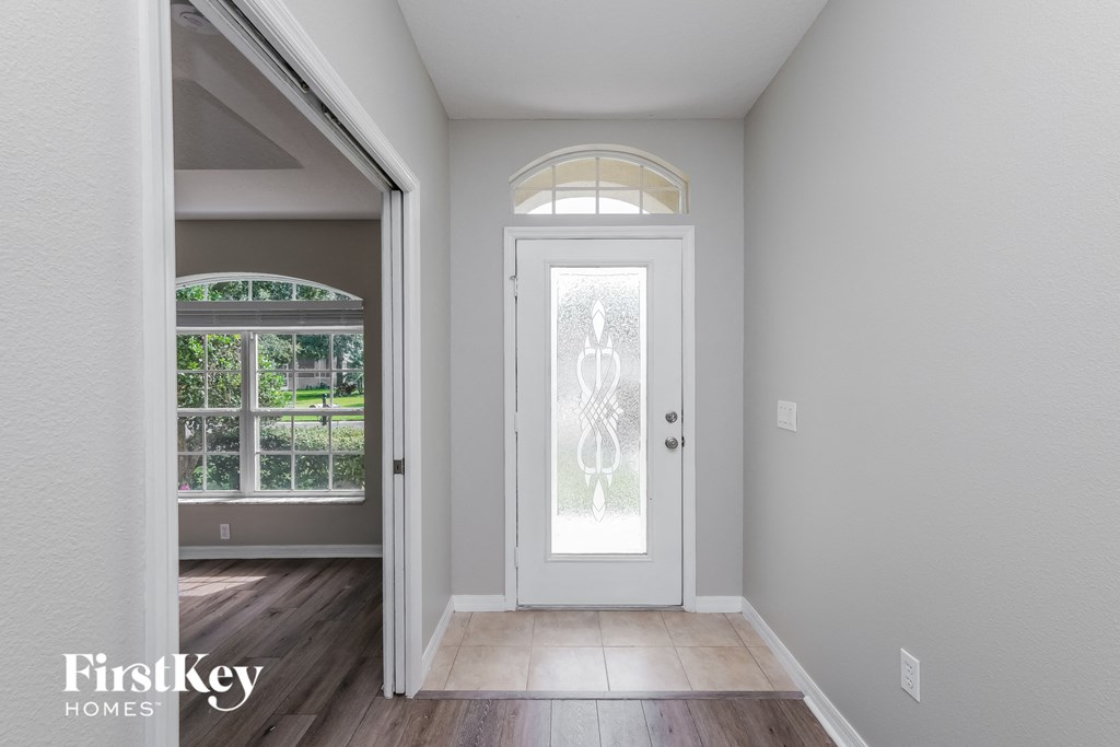 A white door with a glass window is in the middle of a hallway.