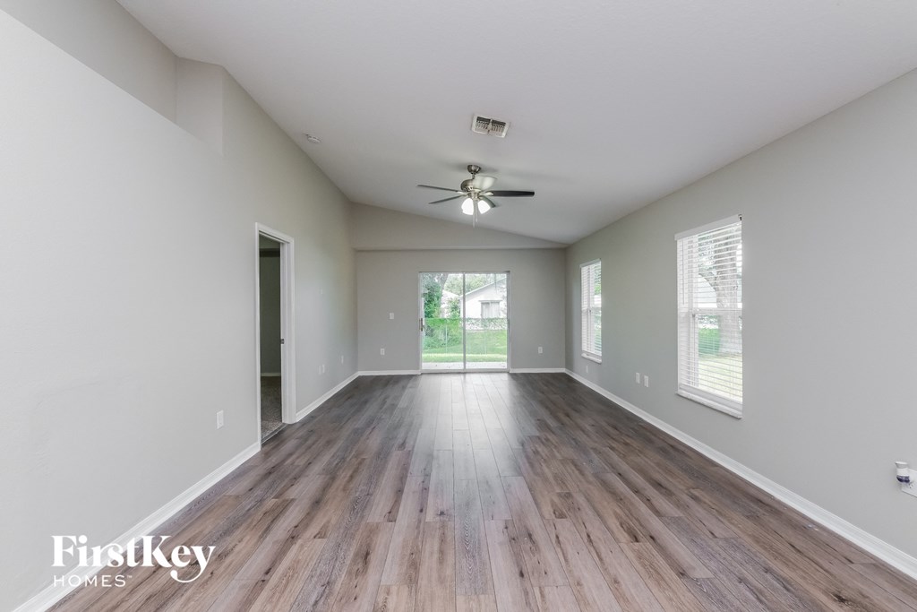 A spacious room with wooden floors and a ceiling fan.