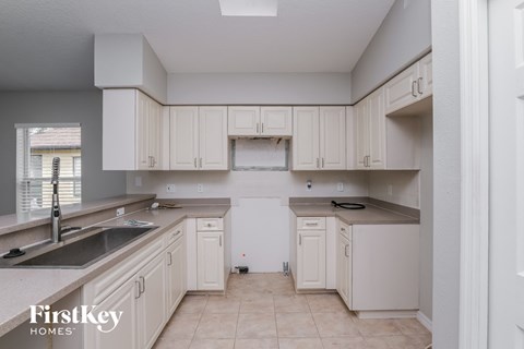 A kitchen with white cabinets and a sink.