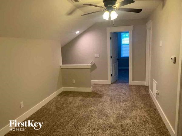 A room with a carpeted floor and a ceiling fan.