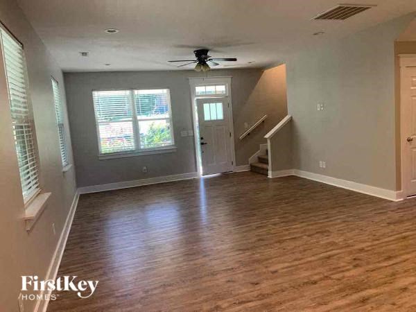A spacious room with wooden flooring and a ceiling fan.
