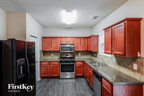 A kitchen with red cabinets and a black fridge.