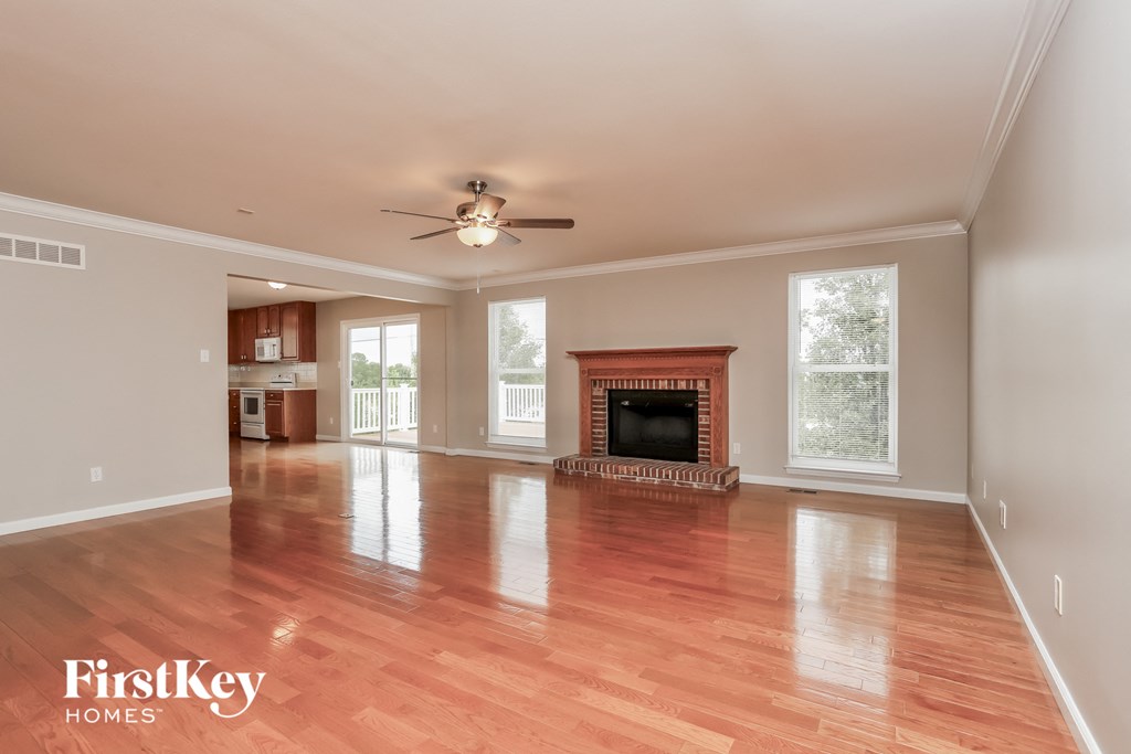 an empty living room with a fireplace and a ceiling fan