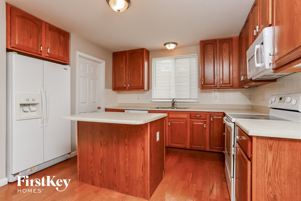a kitchen with wooden cabinets and white appliances and white counter tops