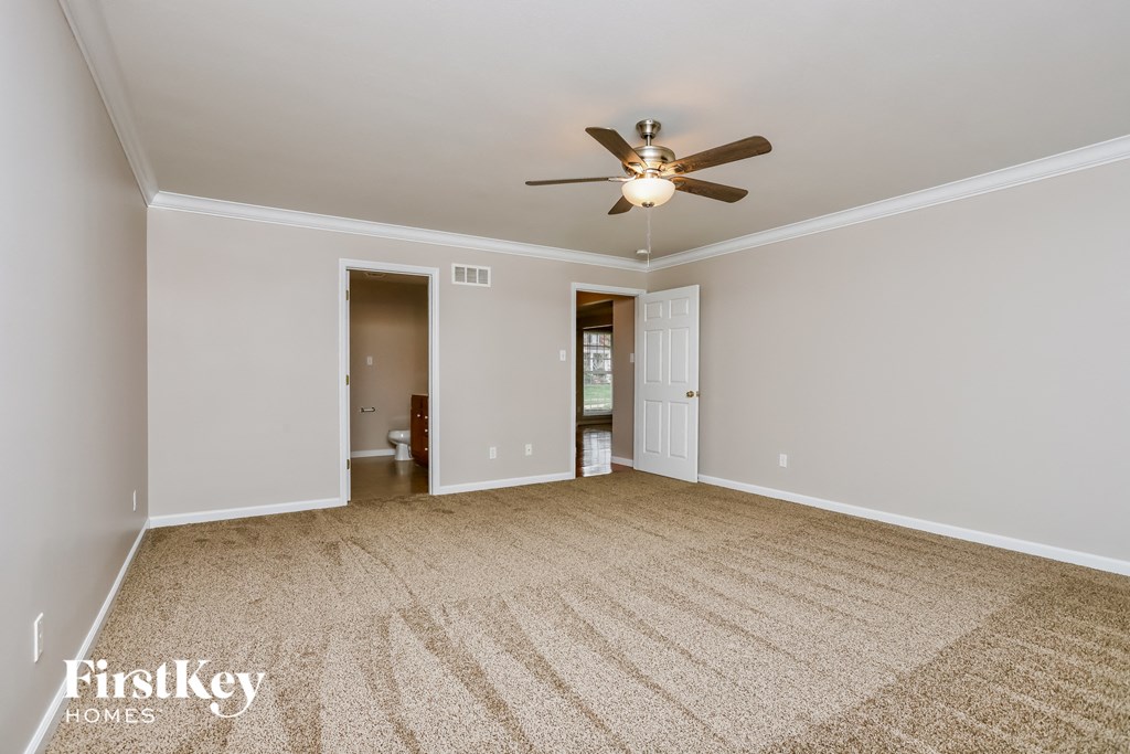 an empty living room with a ceiling fan and a carpet