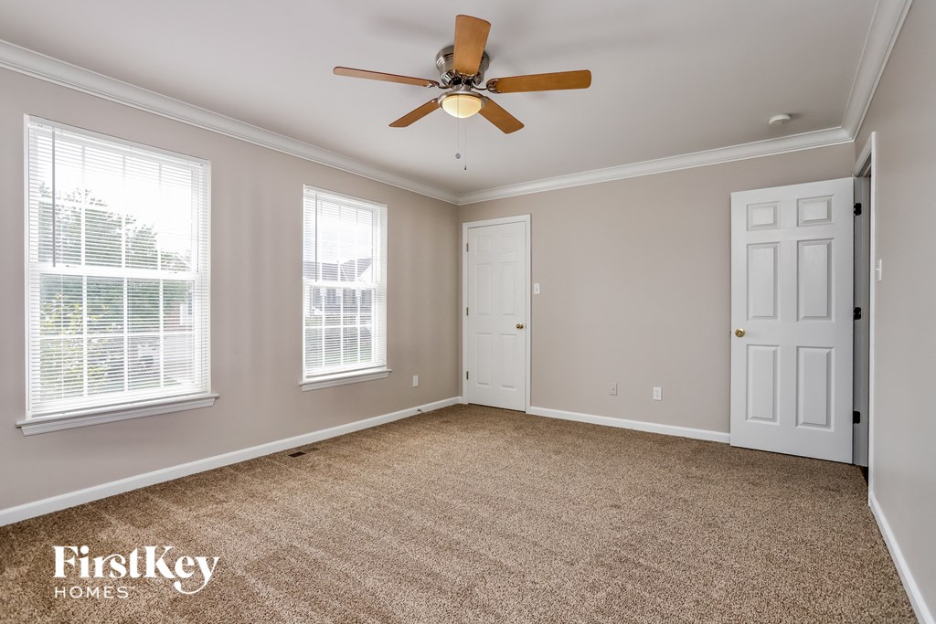 an empty living room with a ceiling fan and two windows