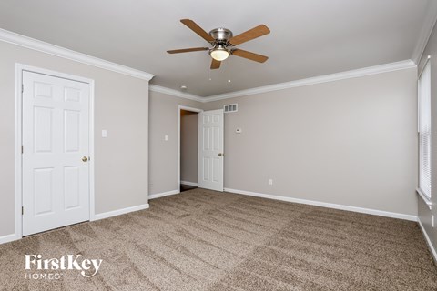 a living room with a ceiling fan and a carpet