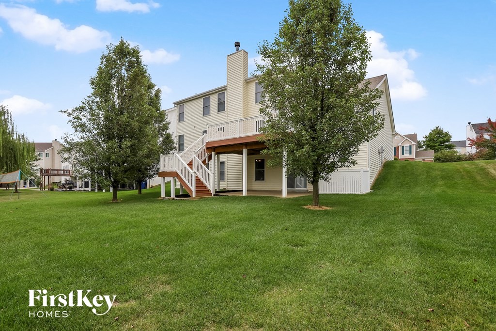 a large lawn in front of a white house with a porch