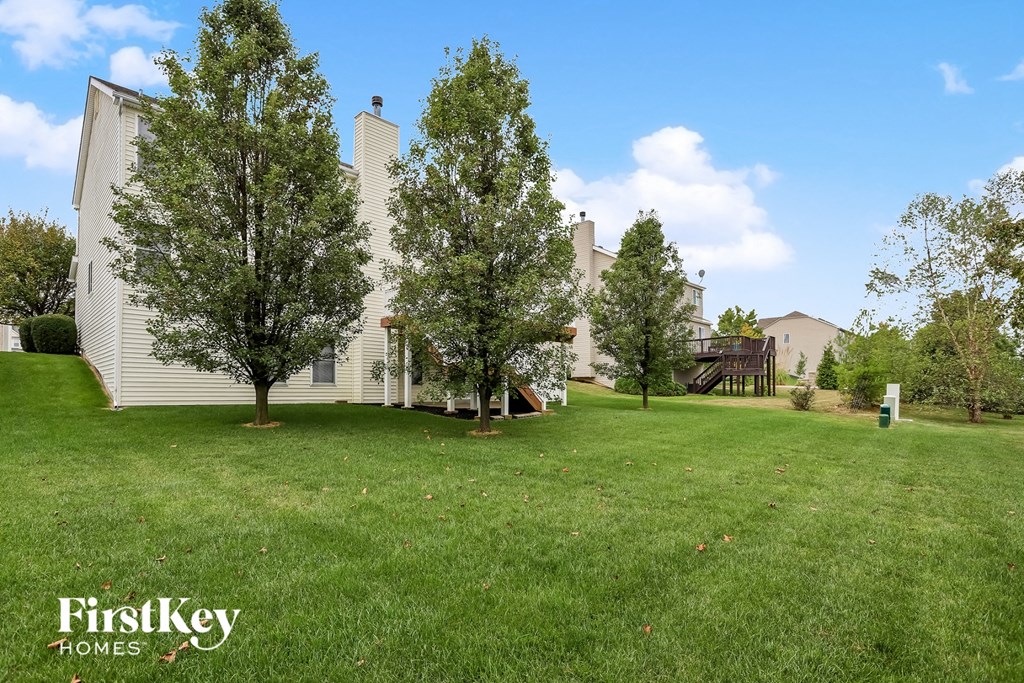 a yard with trees and a house in the background