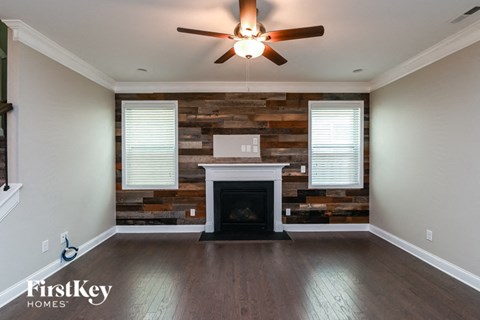 an empty living room with a fireplace and a reclaimed wood wall