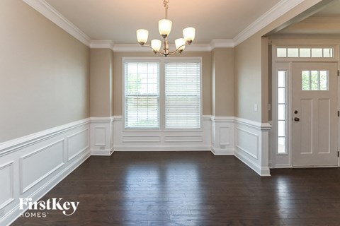 an empty dining room with white walls and a chandelier
