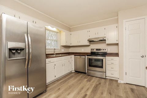 A kitchen with a refrigerator, oven, and cabinets.